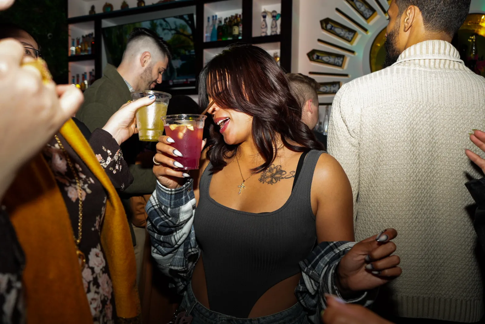 A guest dancing in the bar area with a drink in her hand, friends raising cups around her