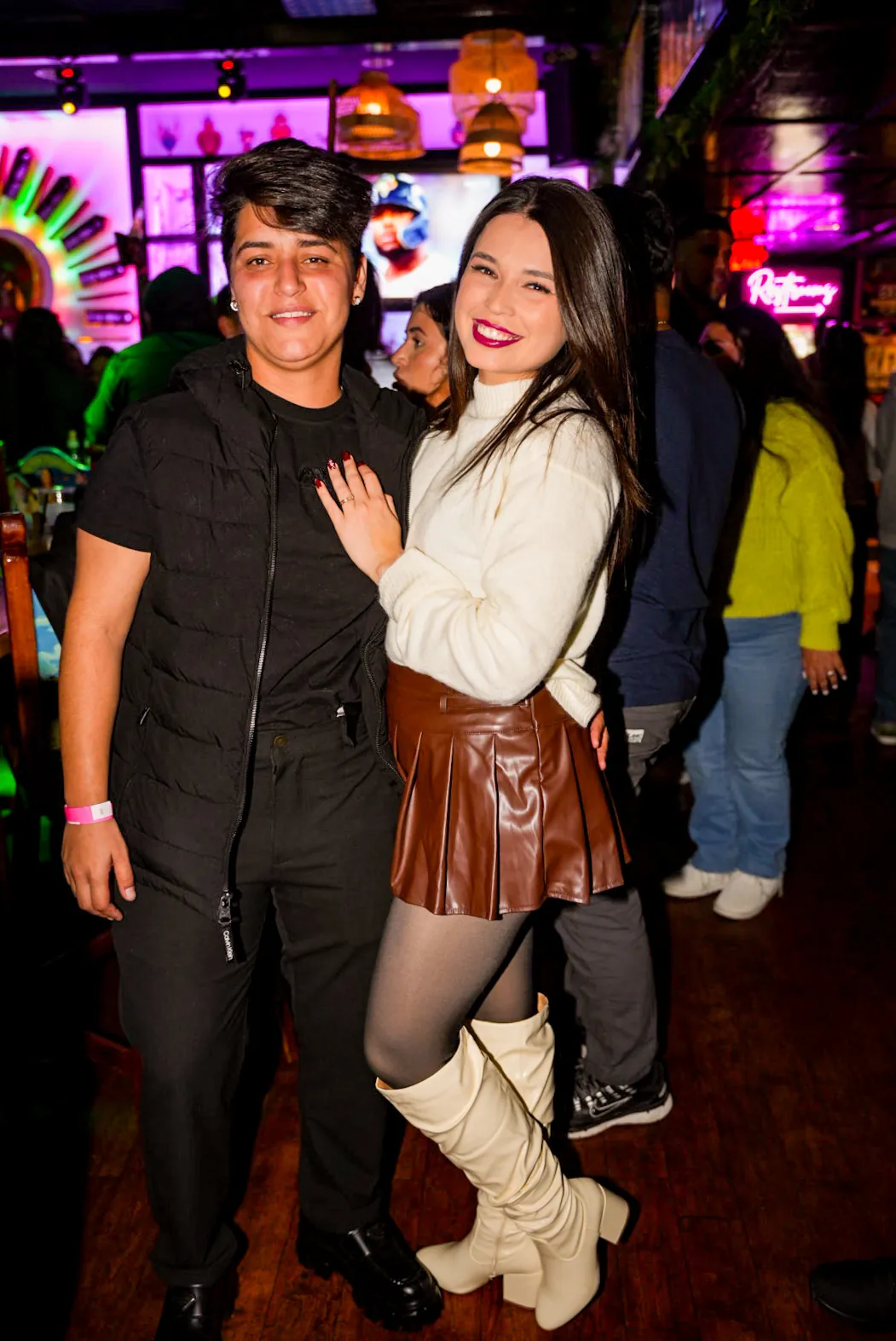 Two friends posing together in the crowded bar area