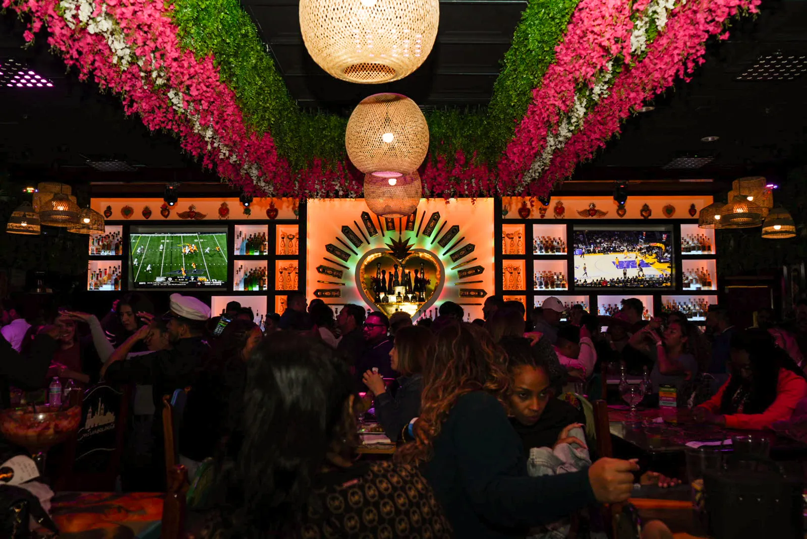 The bar area full from end to end on a busy night, the flower ceiling and lanterns overhead