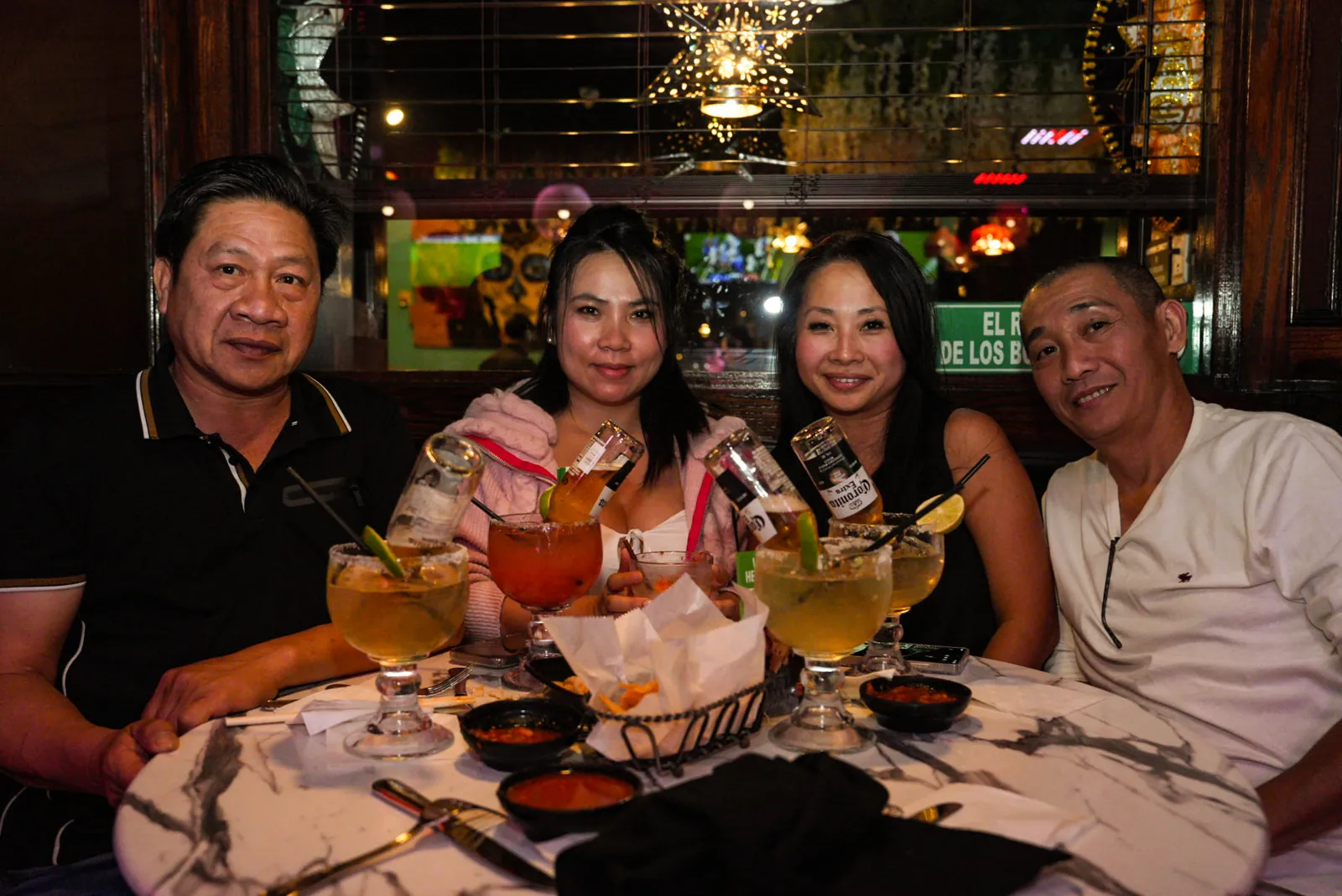 Four guests at a round table with big margaritas and a basket of chips