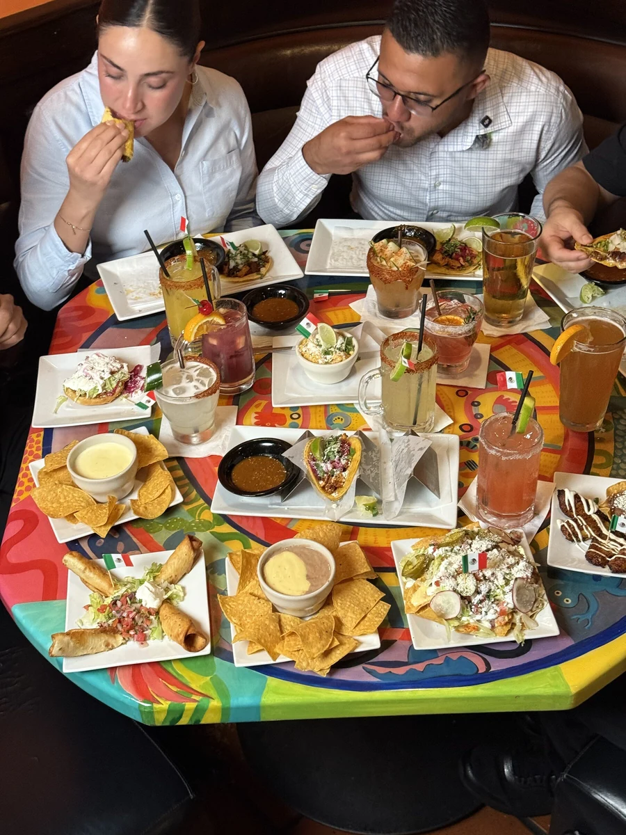 Guests sharing a table of happy hour plates and drinks