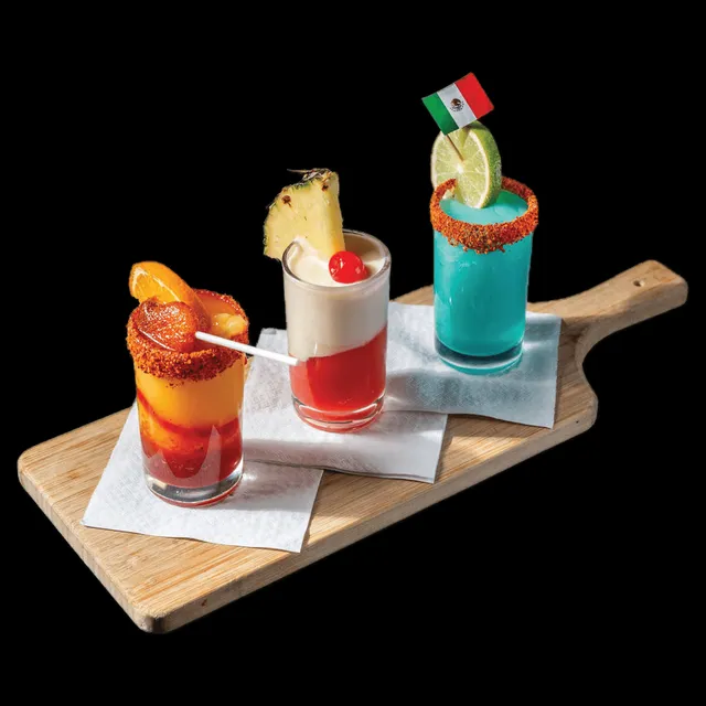 Three small margaritas on a wooden paddle
