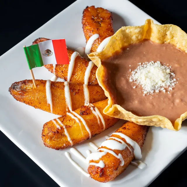 Fried plantains drizzled with crema, with refried beans in a tortilla cup