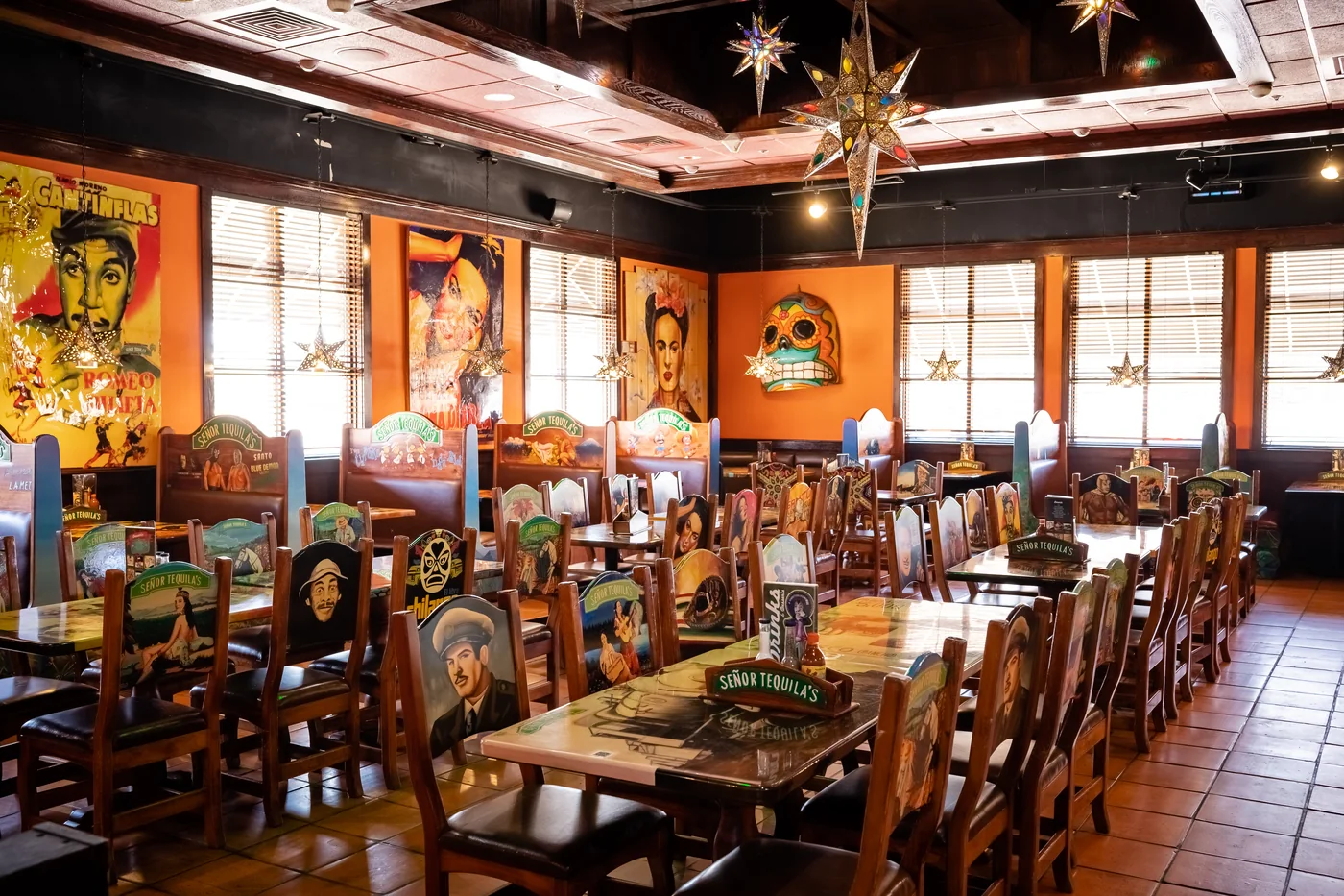 The Mexican Room set for dinner: long tables, painted wooden chairs, a star lantern and hand-painted portraits on the walls
