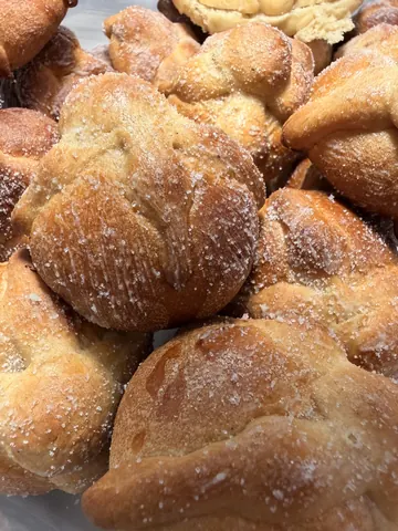 Sugar dusted pan de muerto stacked on a tray, photographed close up